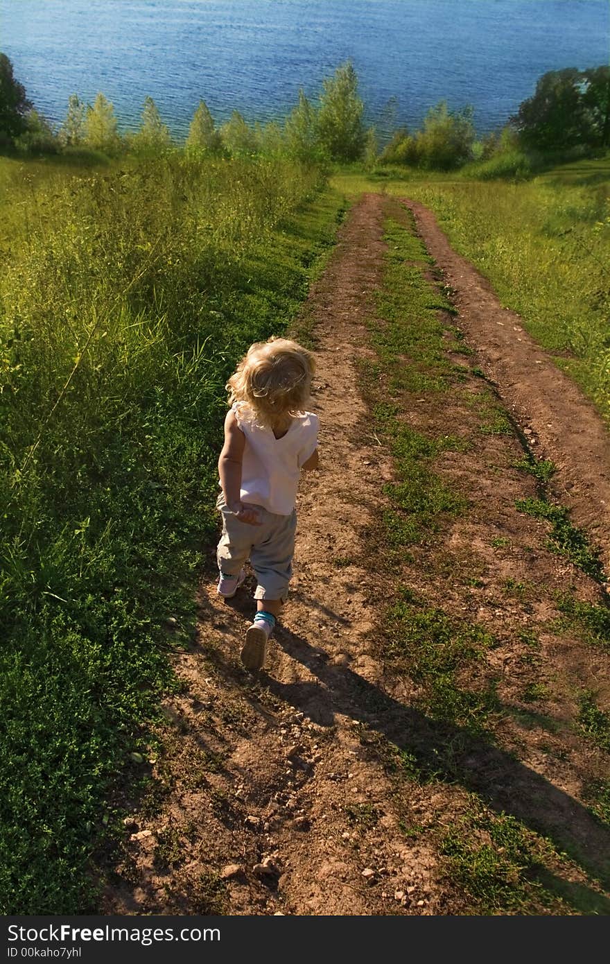 Child runs on road to river. Child runs on road to river.