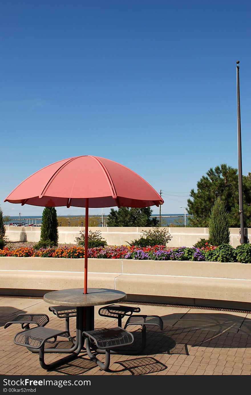 Picnic table with a bright red umbrella to provide shade. Picnic table with a bright red umbrella to provide shade