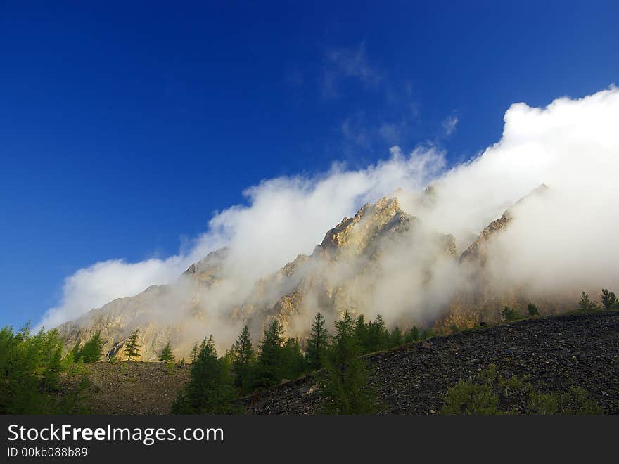 Morning wind blows clouds over rock. Morning wind blows clouds over rock