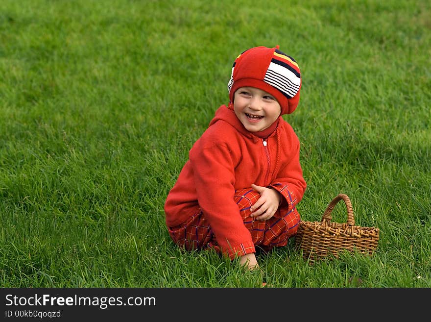 Child sits on a green grass with a basket. Child sits on a green grass with a basket