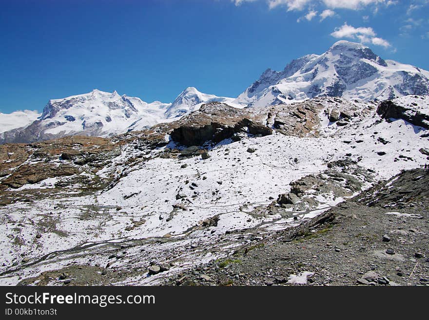 A panoramic view on Alps rocky mountain chain under blue sky. Alps, Switzerland, Europe. A panoramic view on Alps rocky mountain chain under blue sky. Alps, Switzerland, Europe.