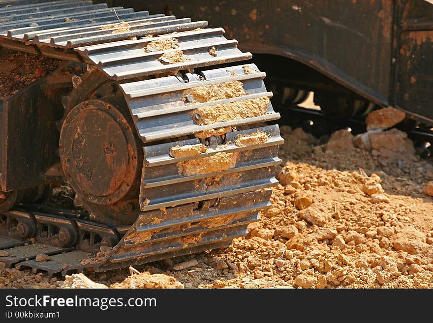 Steel tracks of a front end loader rolling through fresh dirt