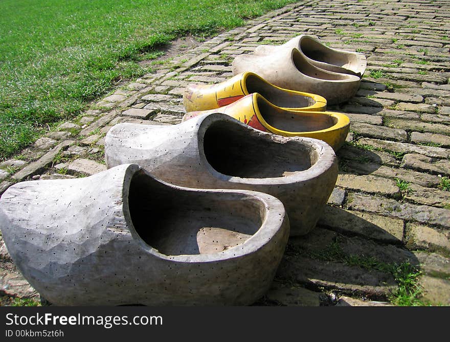 Real original and traditional wooden shoes (some with woodworm) on a brick road. Real original and traditional wooden shoes (some with woodworm) on a brick road