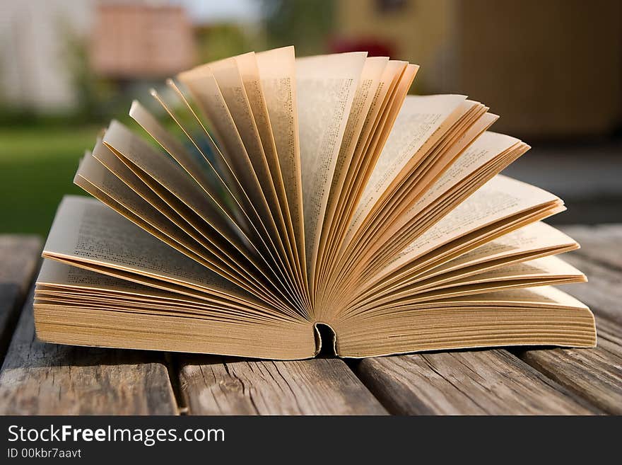 The book is laying on a old wooden table. The book is laying on a old wooden table