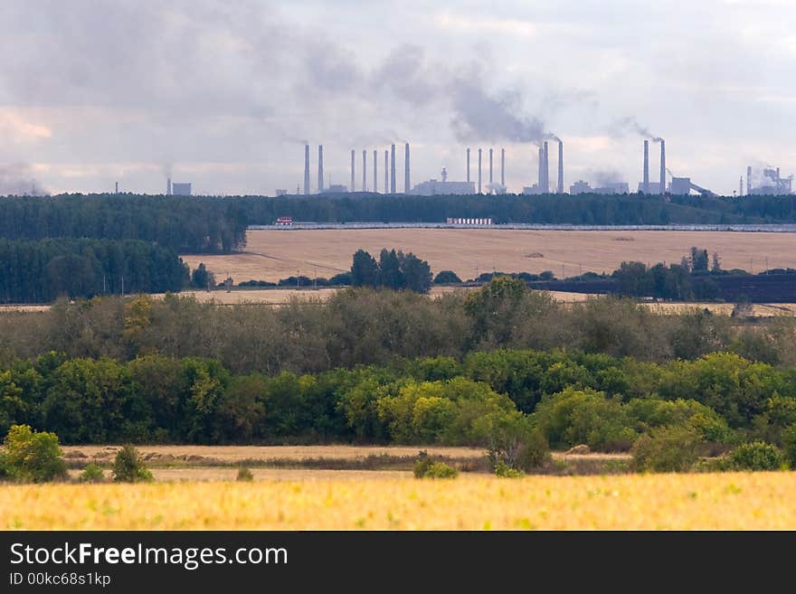 Factory chimneys under autumn fields