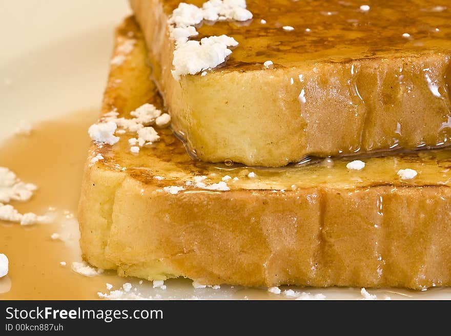 French toast on a white plate with powdered sugar and maple syrup