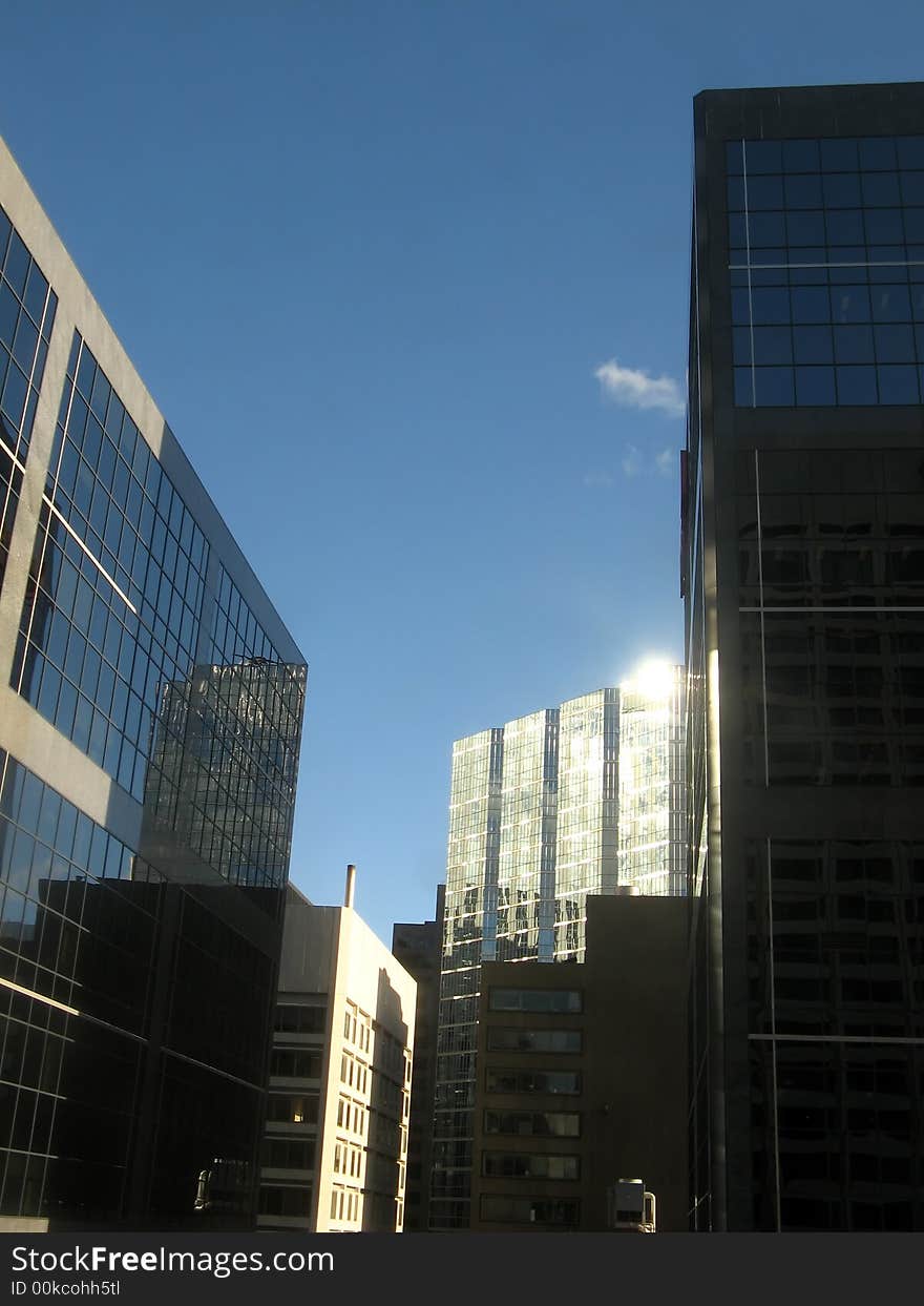 A view of skyscraps from below which reflect the sun