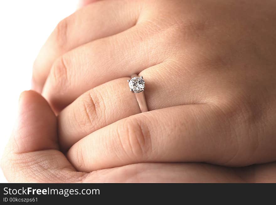 A man holding his fiance's hand with an engagement ring on. A man holding his fiance's hand with an engagement ring on