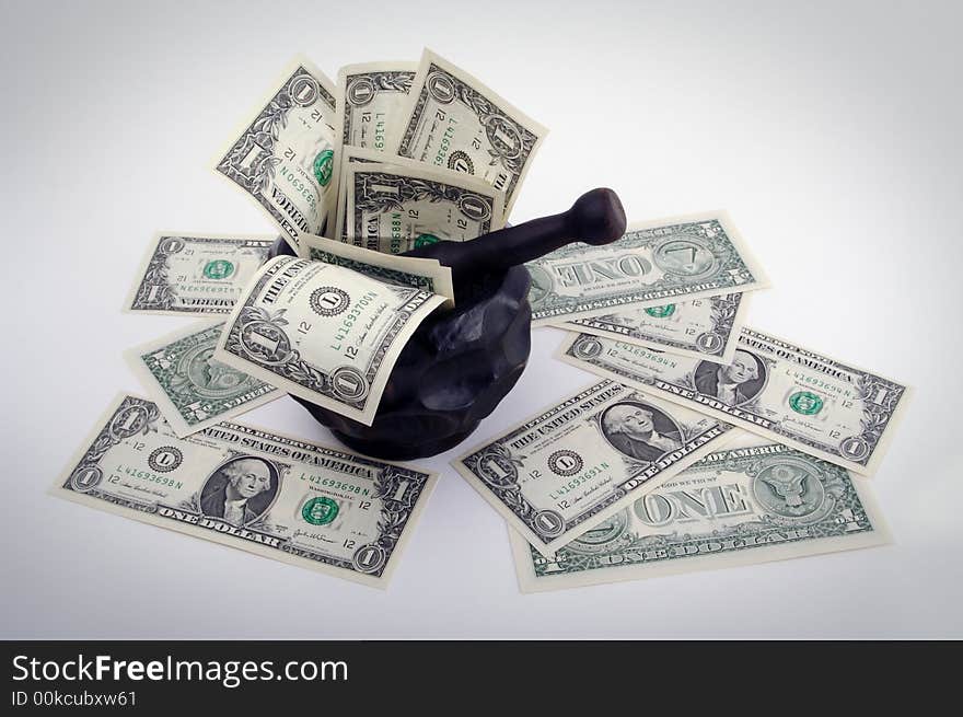 Grinding for Dollars - Wood mortar and pestle containing dollar bills on a white background.