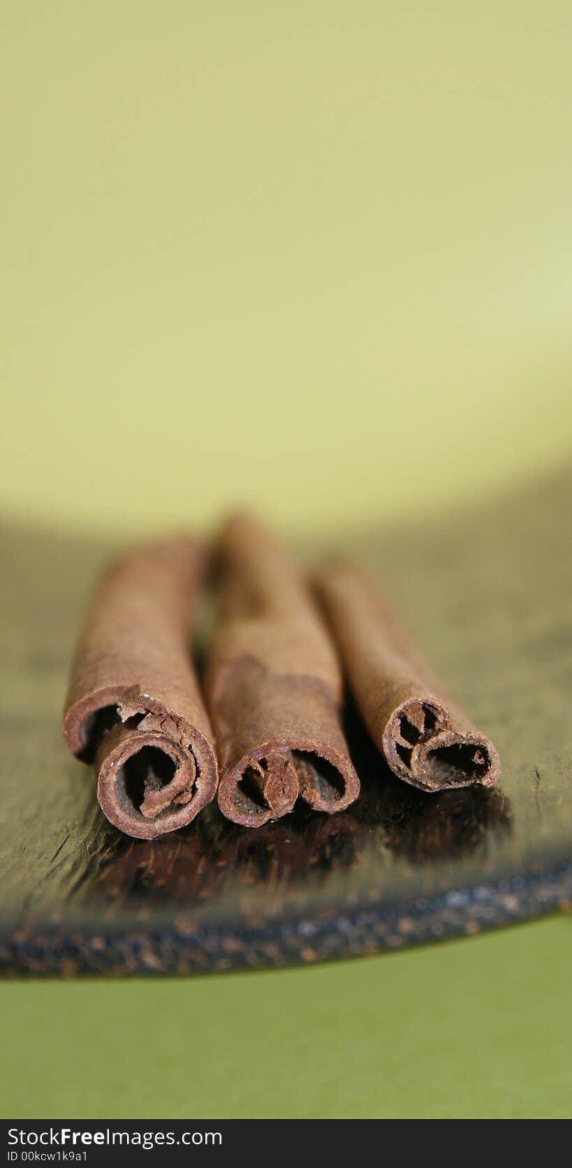 Three cinnamon sticks on the wooden plate