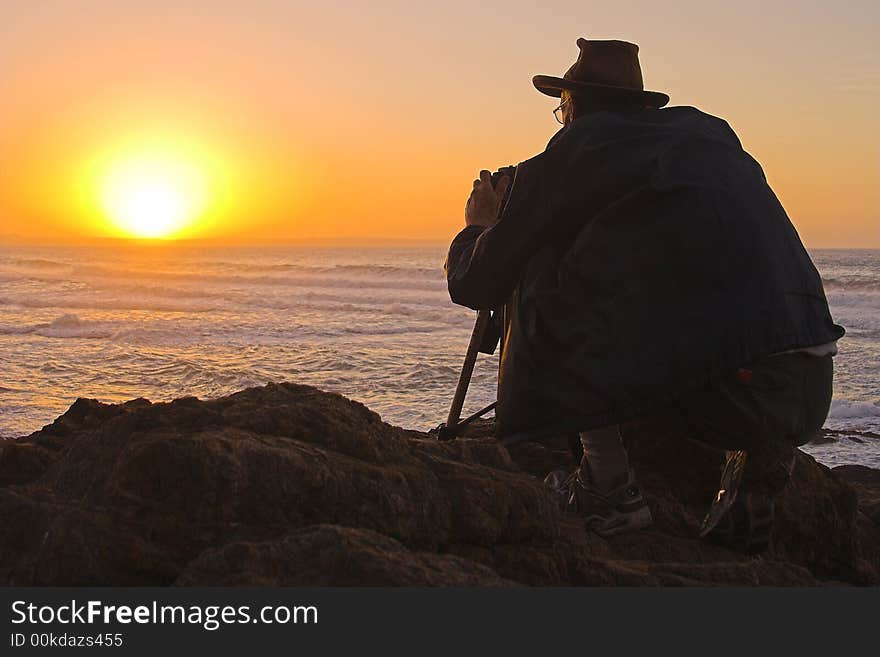 Photographer taking pictures of the sun setting behind the sea. Photographer taking pictures of the sun setting behind the sea