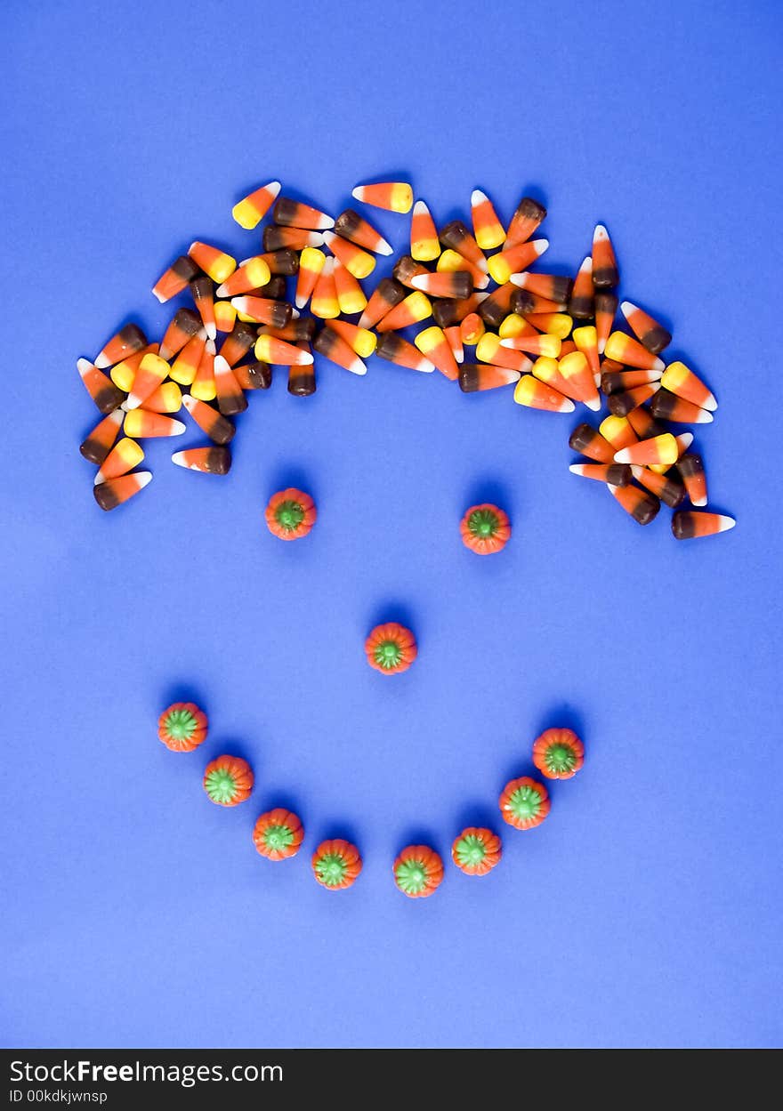 A smily face made with candy, with candy corn hair taken on a blue background. A smily face made with candy, with candy corn hair taken on a blue background.