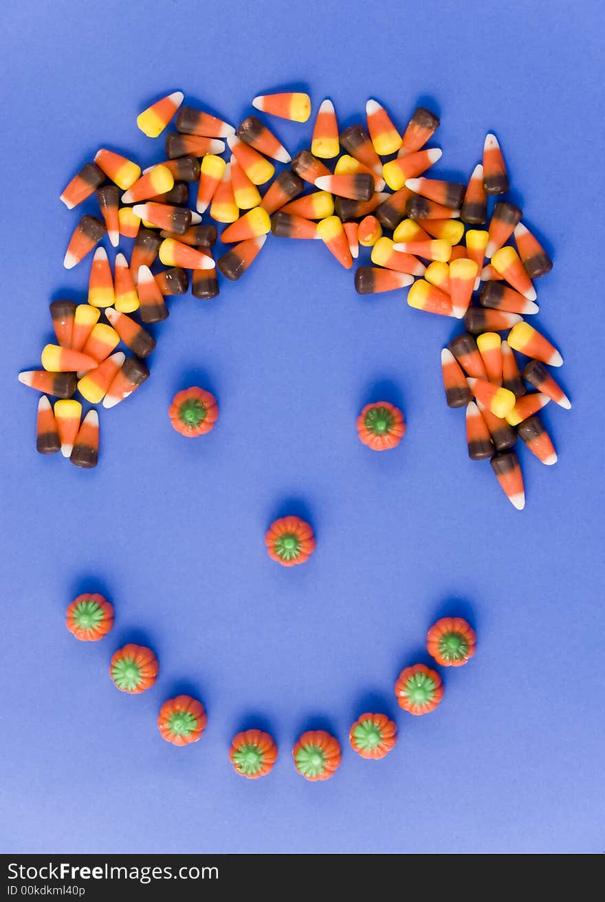 A smily face made with candy, with candy corn hair taken on a blue background. A smily face made with candy, with candy corn hair taken on a blue background.