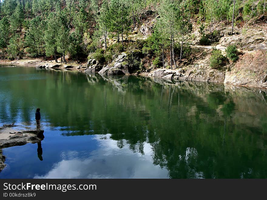 Calm and peaceful waters of a lake with silhouette of a person contemplating nature. Calm and peaceful waters of a lake with silhouette of a person contemplating nature