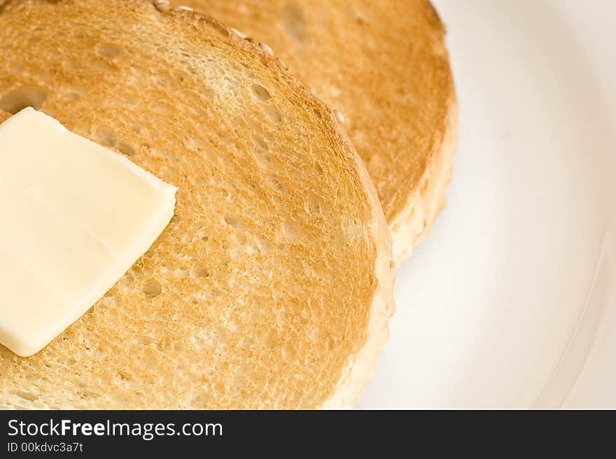 Two slices of toast and a slice of butter on a white plate