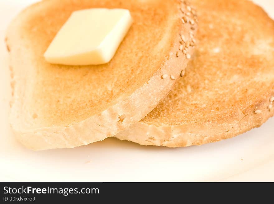 Two slices of toast and a slice of butter on a white plate