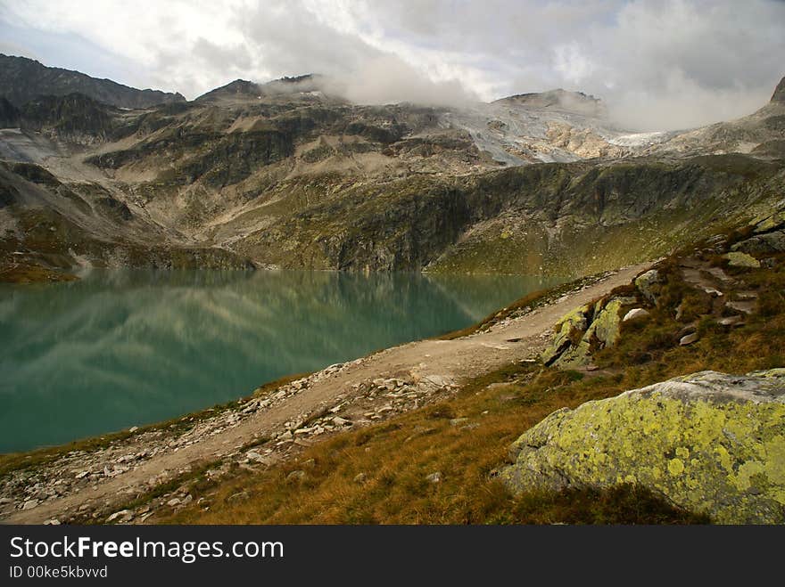 Alpine lake (Weißsee) surrounded by mountains with low clouds.