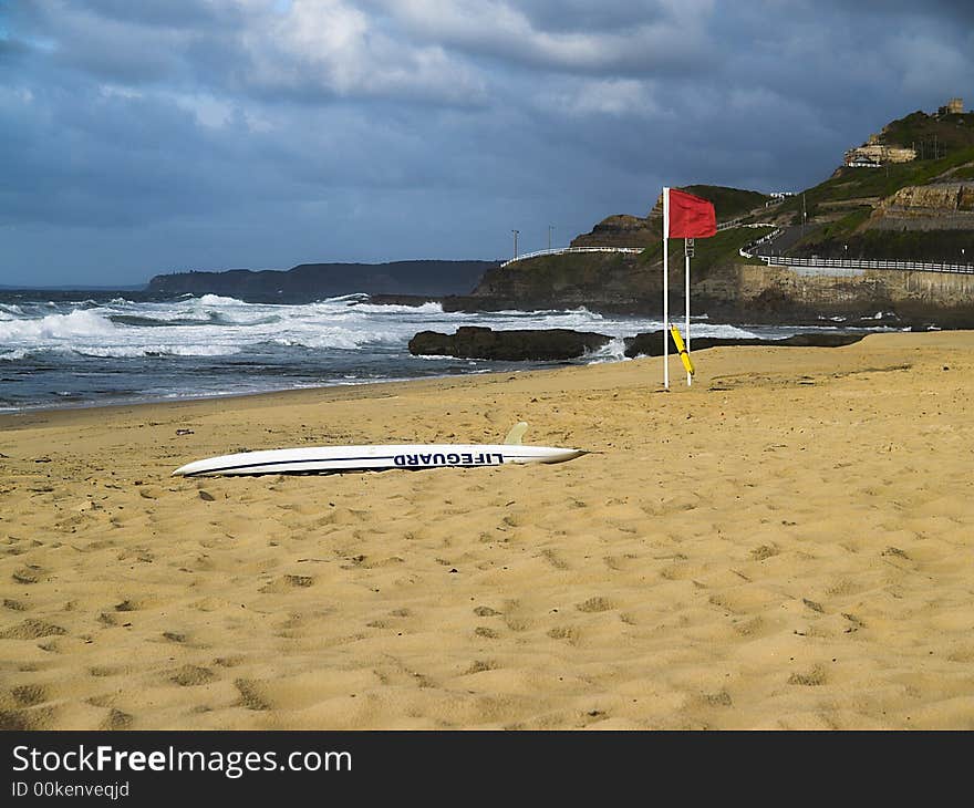 An empty beach with the lifeguard rescue board on the sand