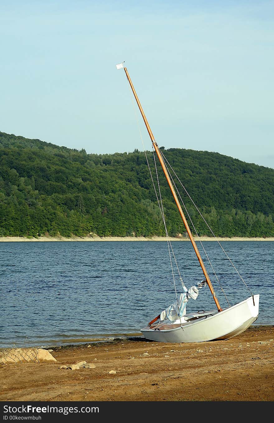 White small boat stranded on sand coast