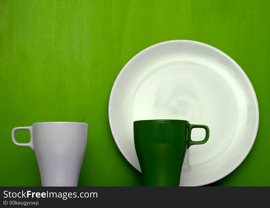 Cups and plate on green background. Cups and plate on green background