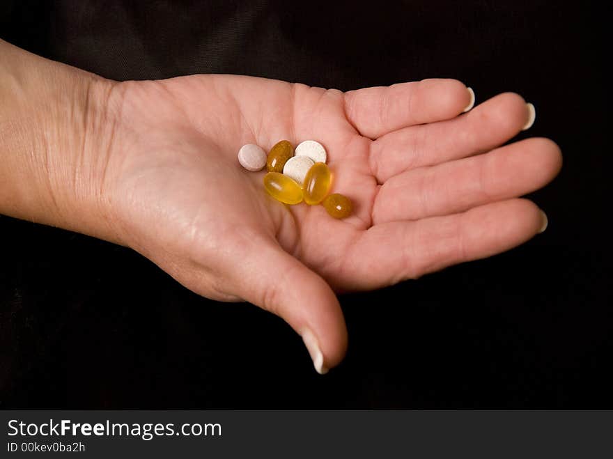 Hand holding pills and tablets on black background. Hand holding pills and tablets on black background