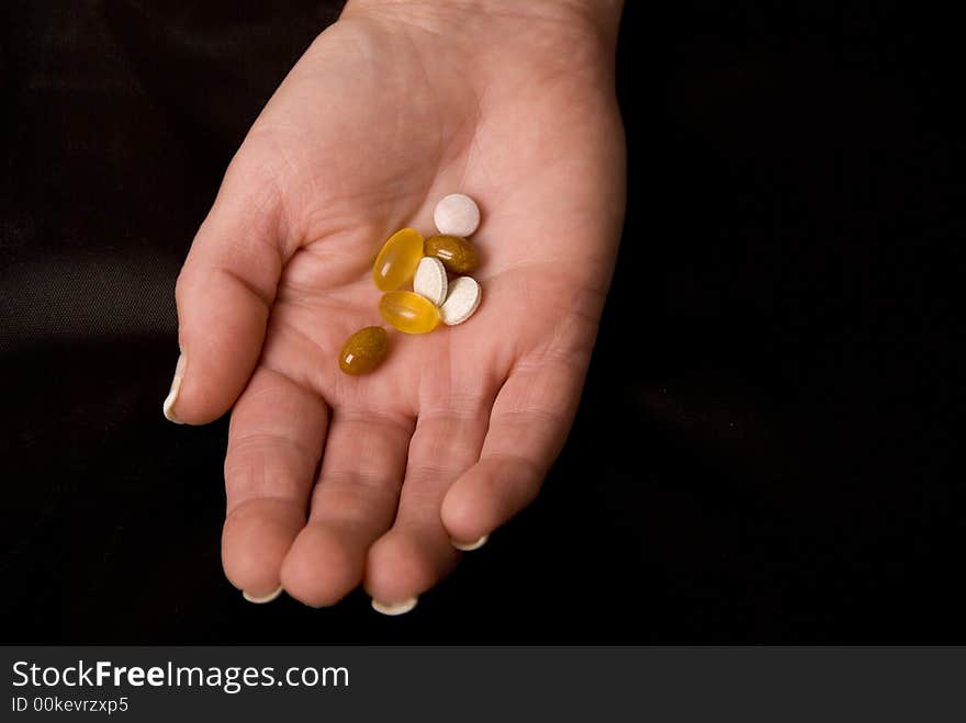 Hand holding pills and tablets on black background. Hand holding pills and tablets on black background