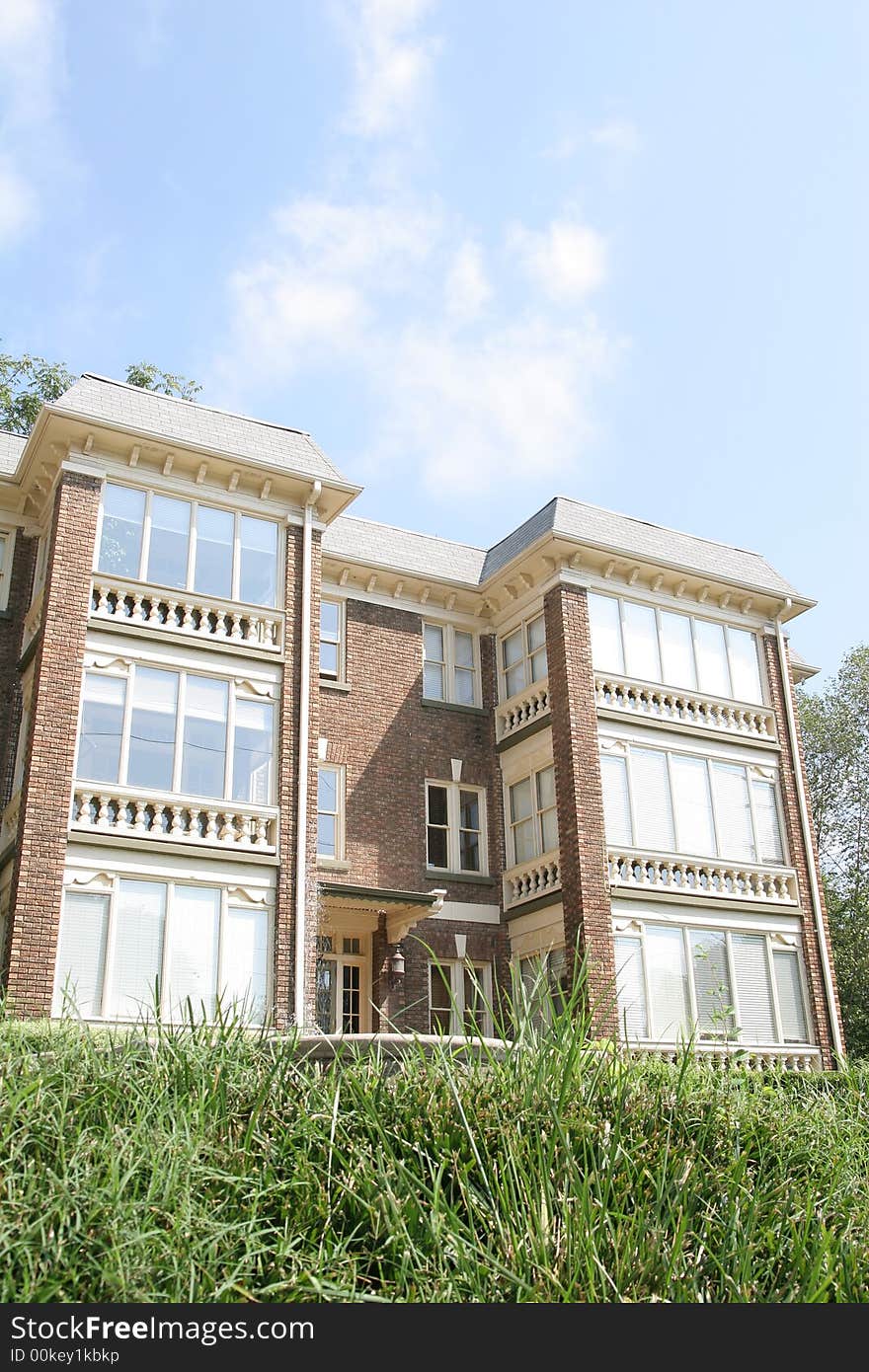 An old brick and glass apartment building on a grassy hill. An old brick and glass apartment building on a grassy hill