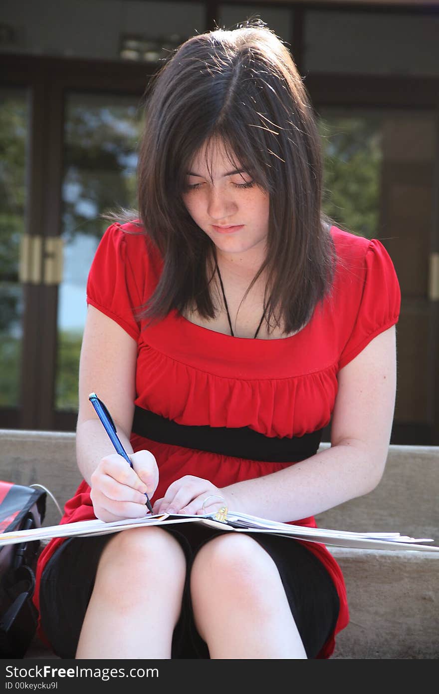 Beautiful 14 year old girl doing homework outside at school. Beautiful 14 year old girl doing homework outside at school.