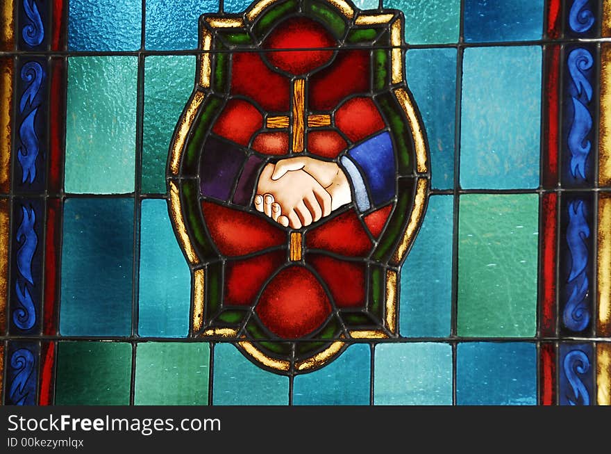 Stain glass window with a center cross and two hands