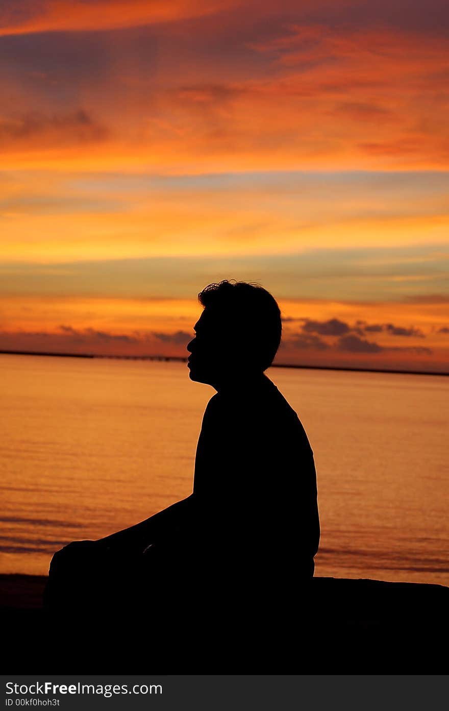 A man sitting by sea in the sunset in Langkawi, Malaysia. A man sitting by sea in the sunset in Langkawi, Malaysia.