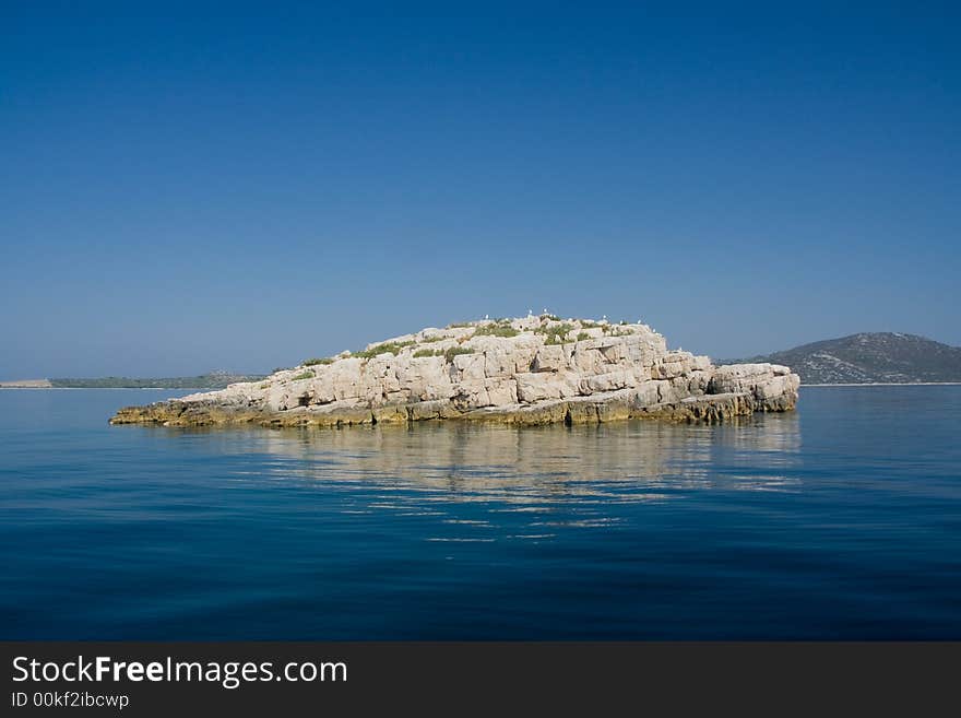 White island in blue sea water. White island in blue sea water.