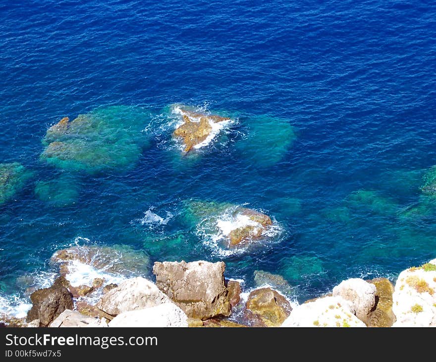 Sea landscape, trasparent and blue water, and stones