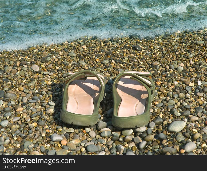 Pair of slipper on beach and wave
