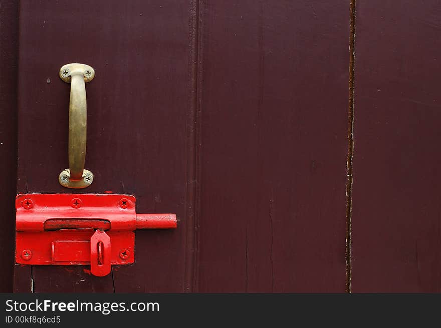 Old red latch lock on wooden door