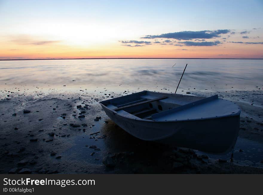 A serene evening landscape with a sunset in the background and a boat in the front. A serene evening landscape with a sunset in the background and a boat in the front