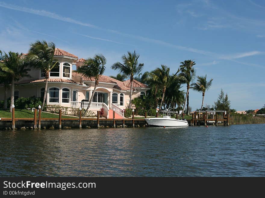 Photo of  a large boat, docked in front of a tropical home. Photo of  a large boat, docked in front of a tropical home