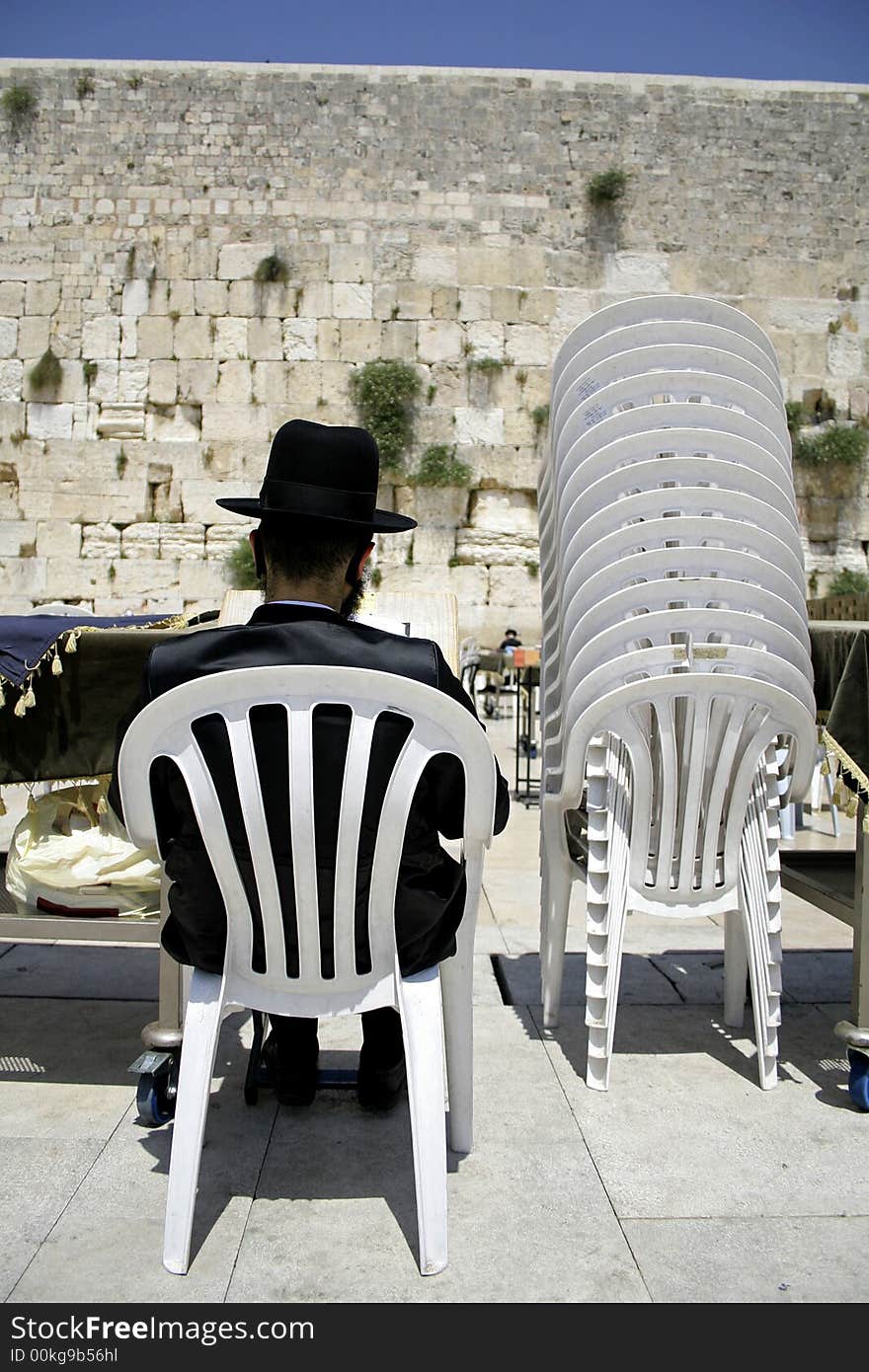 Hasidic jew sitting reading the torah in between plastic chairs at the wailing western wall, jerusalem, israel. Hasidic jew sitting reading the torah in between plastic chairs at the wailing western wall, jerusalem, israel