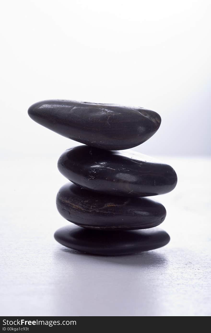 Four stapled, round, smooth black stones. Zen-Style. White background. Reassuring. Four stapled, round, smooth black stones. Zen-Style. White background. Reassuring.