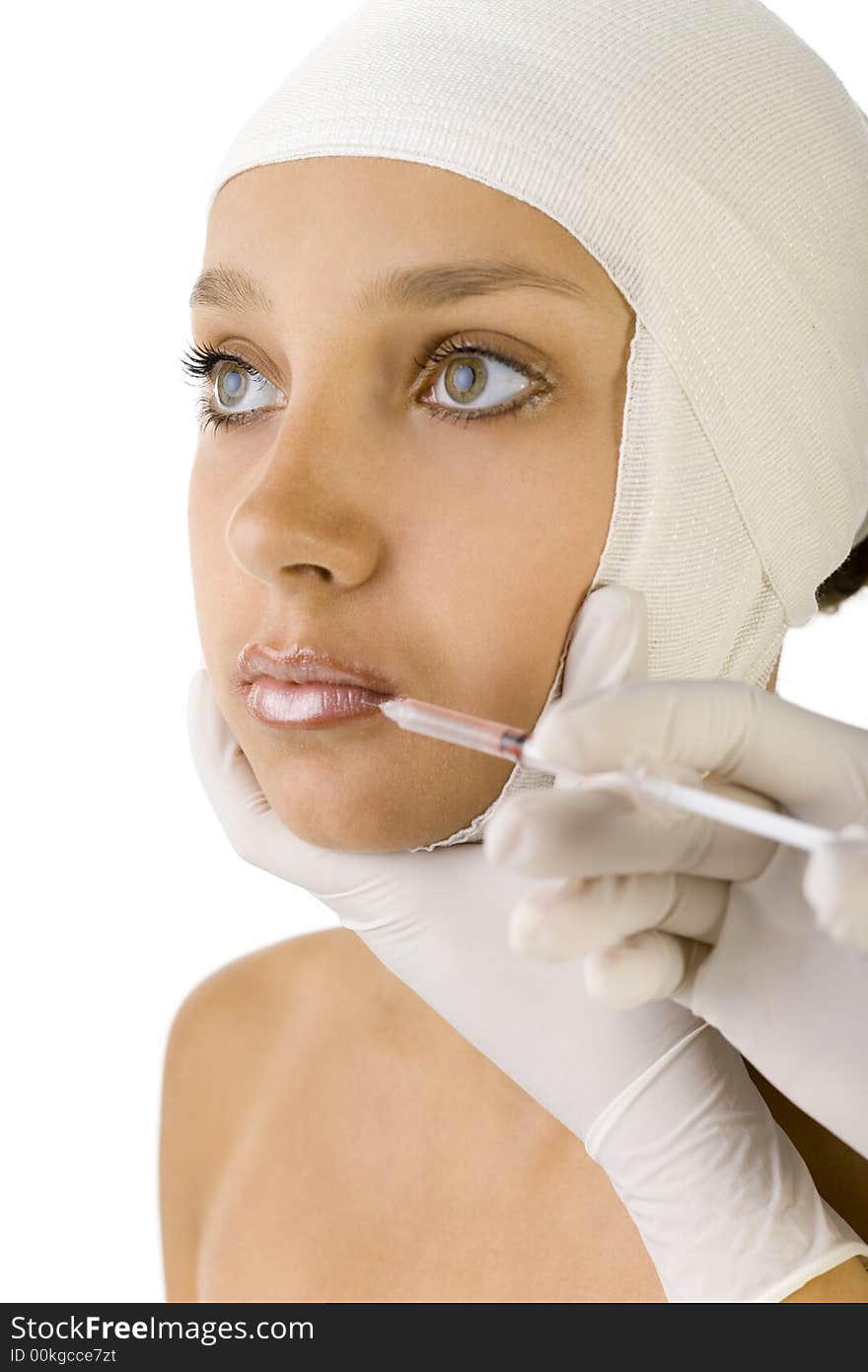 Young, beautiful woman with bandage on head. Somebody is injecting something in her's lips. Side view, white background. Young, beautiful woman with bandage on head. Somebody is injecting something in her's lips. Side view, white background