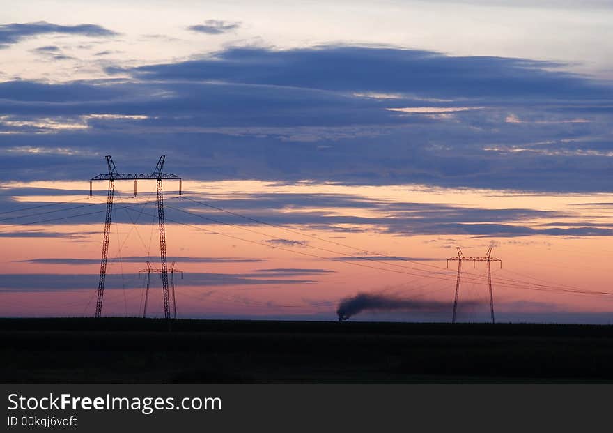 High voltage electricity pylon and power lines on sunset with clouds and smoke. High voltage electricity pylon and power lines on sunset with clouds and smoke