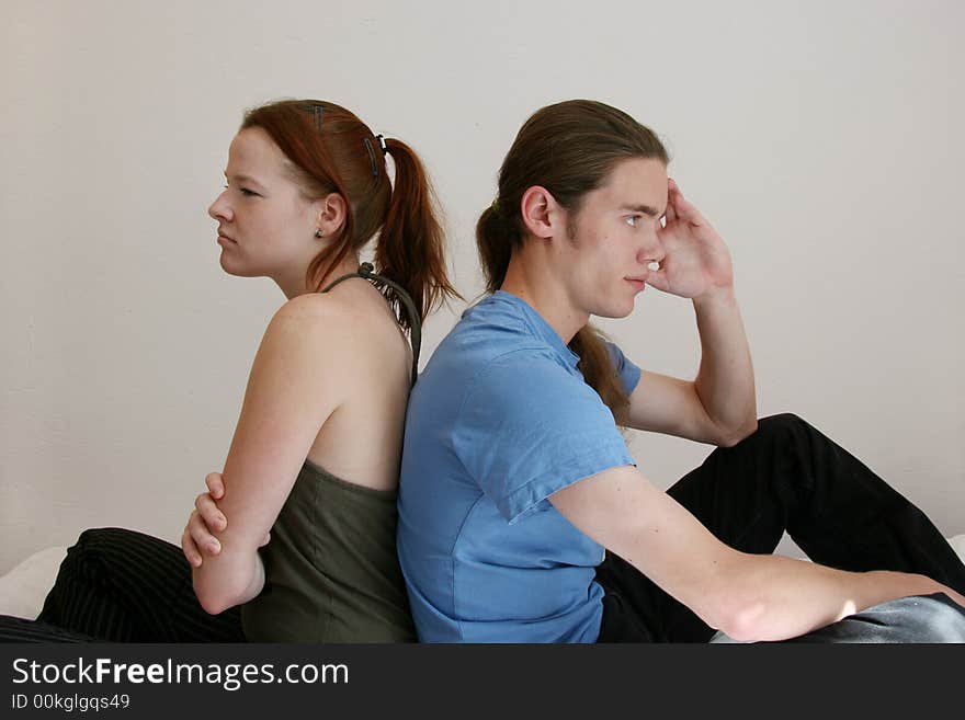 Young man and woman with their backs to each other after an argument. Young man and woman with their backs to each other after an argument.