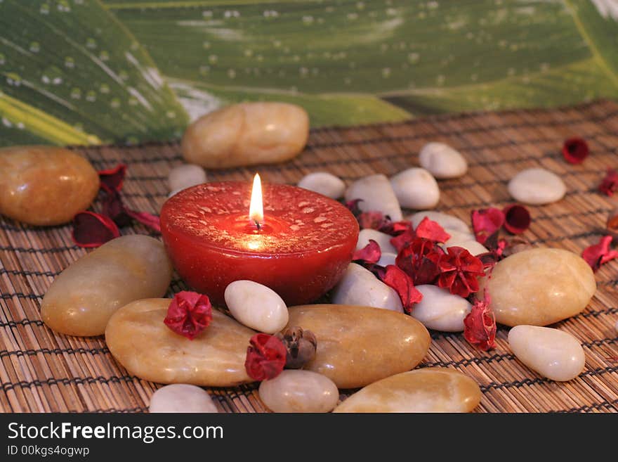 Red candle sourrounded with stones and flowers