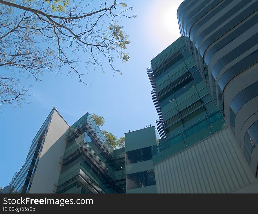 Modern buildings in a city in the shade as the sun approaches high noon.