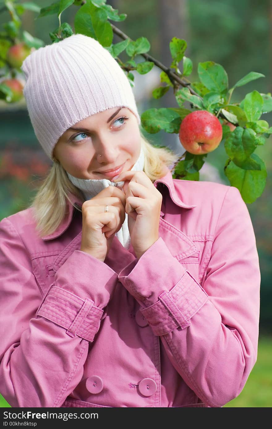 Young girl in pink coat near the apple tree