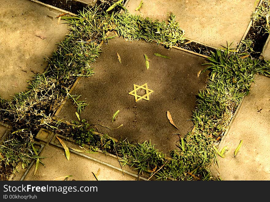 Golden Star of David nestled on square stone laid to rest in grass