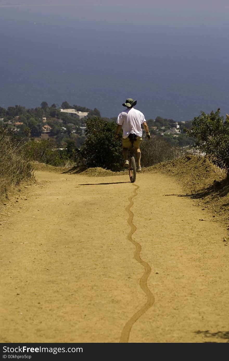 Unicycler and tire tracks on this trail towards the Pacific Ocean. Unicycler and tire tracks on this trail towards the Pacific Ocean