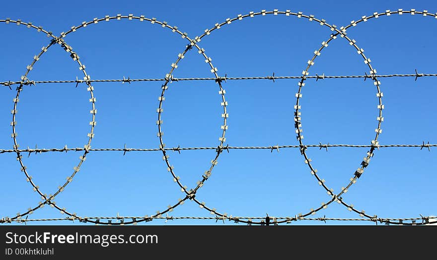 Razor and barbed wire perimiter security fence. Front on view looking slightly up. Razor and barbed wire perimiter security fence. Front on view looking slightly up.