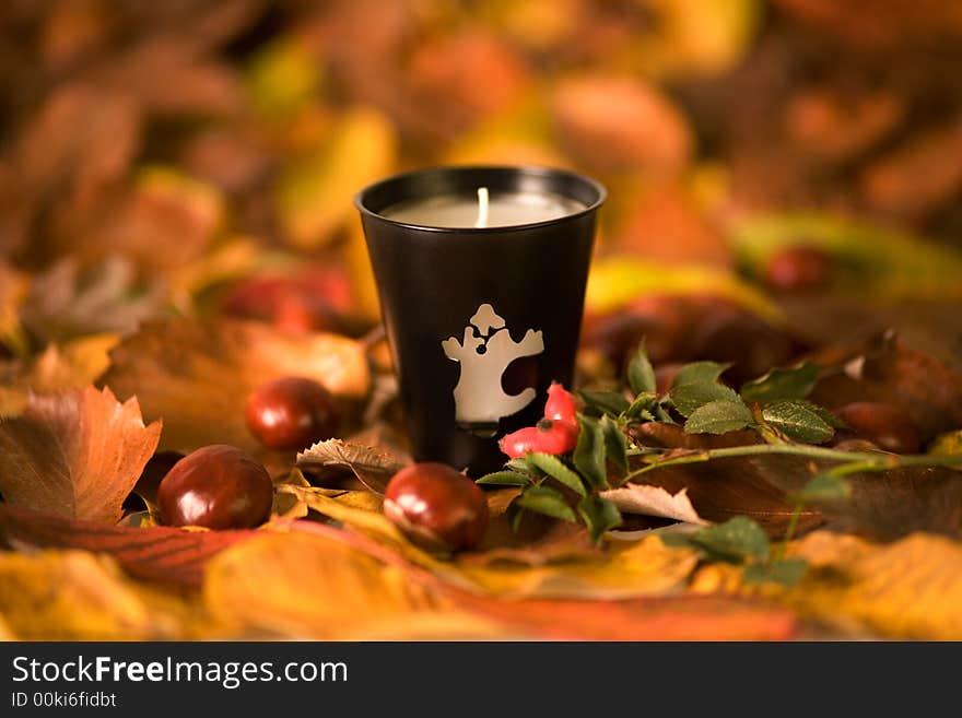 Halloween candle, autumn leaves and chesnuts