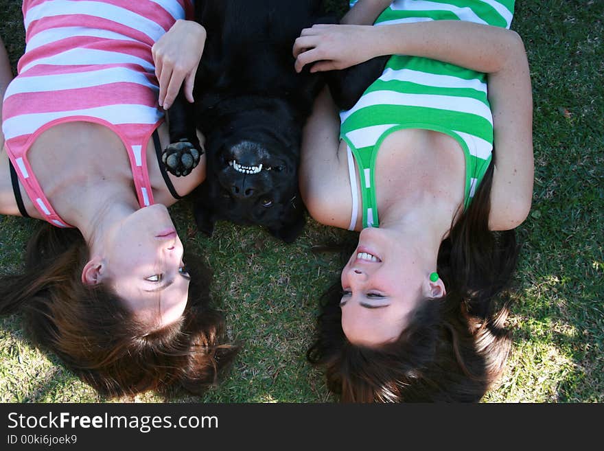 Smiling dog lying in between twin sisters