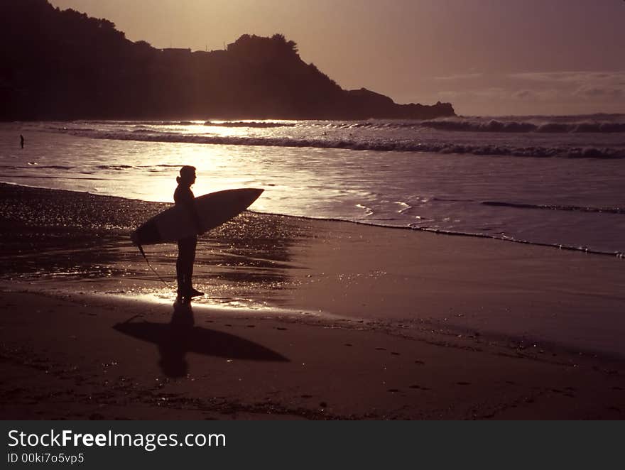 A silhouette of an early morning surfer on a beautiful shoreline. A silhouette of an early morning surfer on a beautiful shoreline.